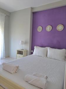 a bedroom with a white bed with a purple wall at Kiki's Place in Nikiti +37 photos