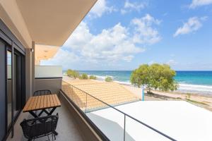 a balcony with a table and chairs and the beach at Dione Seaside Apartments in Hersonissos