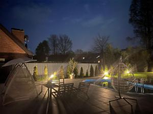 a patio with chairs and a pool at night at LUXUS-RelaxDays-Apartments in Gütersloh