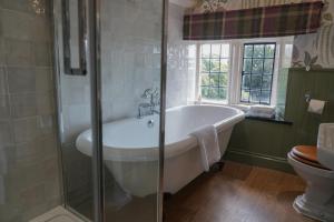 a bathroom with a bath tub and a toilet at The Close Hotel in Tetbury