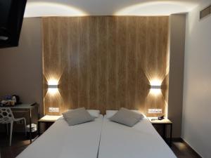 Un dormitorio con una cama blanca con dos luces. en Hotel Medicis, en Barcelona