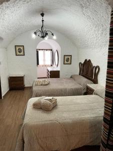 - une chambre avec 3 lits et un lustre dans l'établissement la cueva de guadix, à Guadix