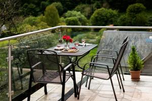 a table and two chairs on a balcony with roses at 2 St Elmo Lodge in Salcombe