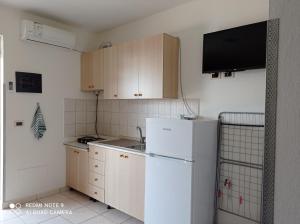 a kitchen with a white refrigerator and a tv at A & H Apartments Velipoje in Velipojë