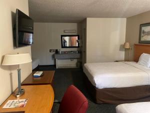 a hotel room with two beds and a desk with a lamp at Skyway Inn - Seatac in SeaTac