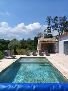 a swimming pool with chairs and a house at Villa au calme in Montauroux