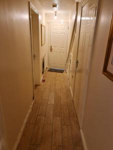 a hallway with a wooden floor and a white door at SOFT PILLOW in North Woolwich