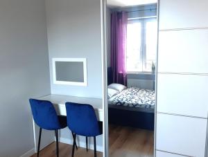 Habitación con mesa y 2 sillas azules en Apartament Wawa, en Varsovia