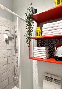 bagno con doccia e mensola rossa con asciugamani di Aria Di Casa a Roma