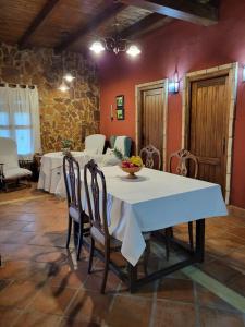 a dining room with a white table and chairs at La Buganvilla, descanso entre olivares in Hornachuelos