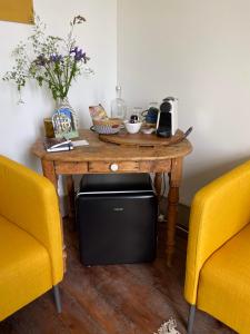 a wooden table with a television and two chairs at Le Brasseur Logements in Saint-Caprais