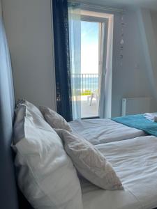 a bed with white sheets and pillows next to a window at Apartament NaFali in Niechorze