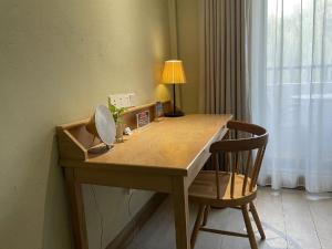 a wooden desk with a chair and a lamp at EBO Hotel Zijin gang Asian Games Park Store Zhejiang university in Hangzhou