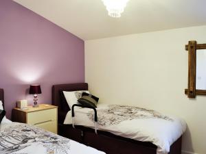 a bedroom with two beds and a table with a lamp at The Retreat in Woolaston