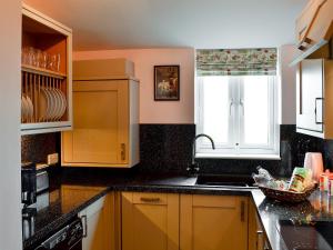 a kitchen with yellow cabinets and a sink and a window at The Outlook in Woolaston