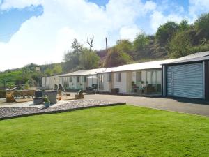 un edificio con un césped verde delante de él en The Retreat, en Woolaston