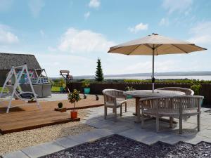 a patio with a table and an umbrella and a playground at The Outlook in Woolaston