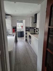 a kitchen with white cabinets and a wooden floor at Margate Town House in Kent