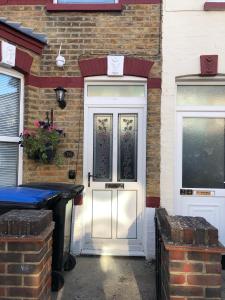 a white front door of a brick house with two windows at Margate Town House in Kent