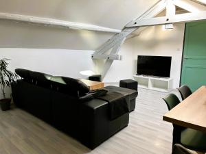 - un salon avec un canapé noir et une télévision dans l'établissement Appartement climatisé Le Gambetta, à Pont-à-Mousson