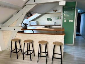 a bar with three stools in front of a kitchen at Appartement climatisé Le Gambetta in Pont-à-Mousson