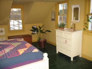 a bedroom with a bed and a dresser and windows at Private setting on country farm near Rhinebeck in Clinton Corners