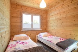 um quarto com 2 camas num chalé de madeira em Kalimera em Sarbinowo