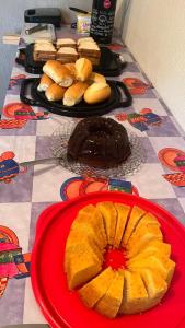 a table topped with plates of cake and buns at Hope Hostel Guarapari in Guarapari