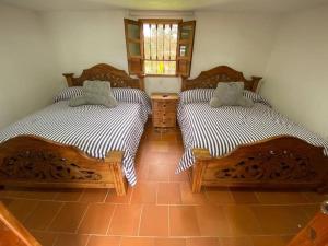 two twin beds in a room with a tile floor at Linda Casa Colonial Remodelada in Guasca