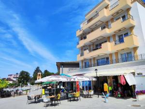 a building with chairs and umbrellas in front of it at Аpartment Bella Vista in Obzor