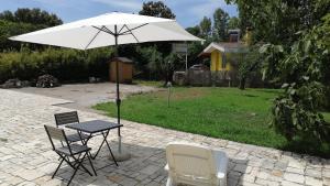 una mesa, sillas y una sombrilla en el patio en Delizioso Open Space da Letizia, en Pomezia