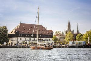 ein Boot im Wasser vor einem Gebäude in der Unterkunft Stadthotel in Konstanz