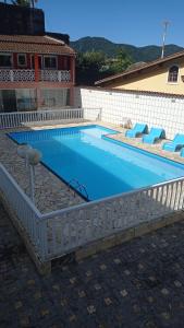 a swimming pool with a white fence around it at Suítes Ubatuba Praia da Lagoinha in Ubatuba