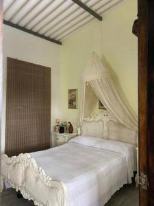1 dormitorio con 1 cama blanca con dosel en Linda Casa Campestre, en Anolaima