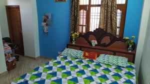 a bedroom with a bed with a blue wall at Kanta riverside Home stay in Pālampur
