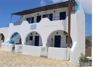 ein weißes Gebäude mit blauen Türen und Fenstern in der Unterkunft Meltemi Rooms and Studios in Anafi