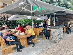 un grupo de personas sentadas en una mesa bajo un paraguas en Hotel Enzian, en Landeck