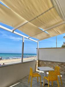 een patio met een tafel en stoelen en het strand bij Vista Mare in Casalabate