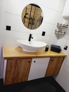 een badkamer met een wastafel en een spiegel op een aanrecht bij Przytulny domek w Brajnikach 86 37 in Jedwabno