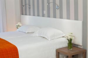 a white bed with a vase of flowers on a table at Princessa Vera Hotel Apartments in Paphos