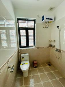 a bathroom with a toilet and a shower and a window at Hương Cảng Homestay in Hai Phong