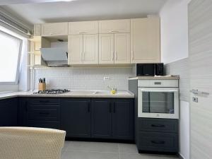 Una cocina con gabinetes blancos y un horno de estufa. en GlamArt Apartment, en Craiova