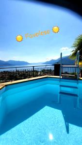 a blue swimming pool with a view of the water at Sole & Lago-Lake in Maccagno Superiore