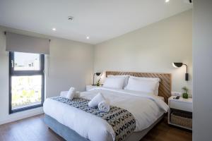 a white bedroom with a large bed and a window at Campo Premium Stay Private Pool Villas in Kos