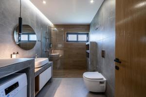 a bathroom with a toilet and a sink and a mirror at Campo Premium Stay Private Pool Villas in Kos