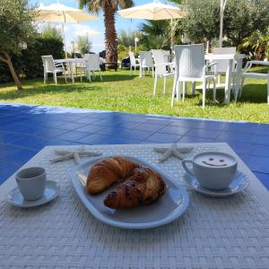 una mesa con un plato de comida y dos tazas de café en B&B Il Gabbiano, en Cittadella del Capo