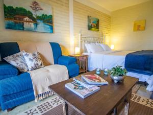 a bedroom with a bed and a couch and a table at Pousada VillaSerrana in Monte Verde