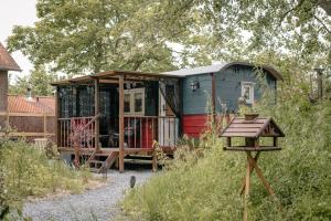 a green and red tiny house in a yard at Pipowagen de Zwerveling aan zee in Oostkapelle