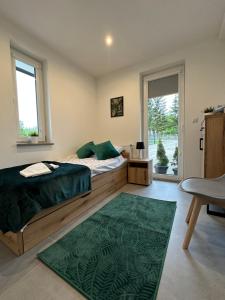 a bedroom with a bed and a green rug at Domki u Edzi in Krajno-Zagórze