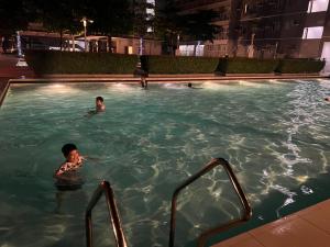 zwei Personen schwimmen nachts im Pool in der Unterkunft MISR Suite QC in Manila